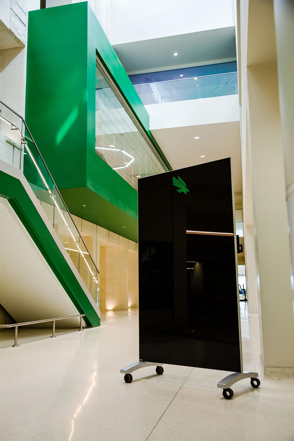 Clarus go! Mobile black rolling glassboard with UNT green logo in college common area